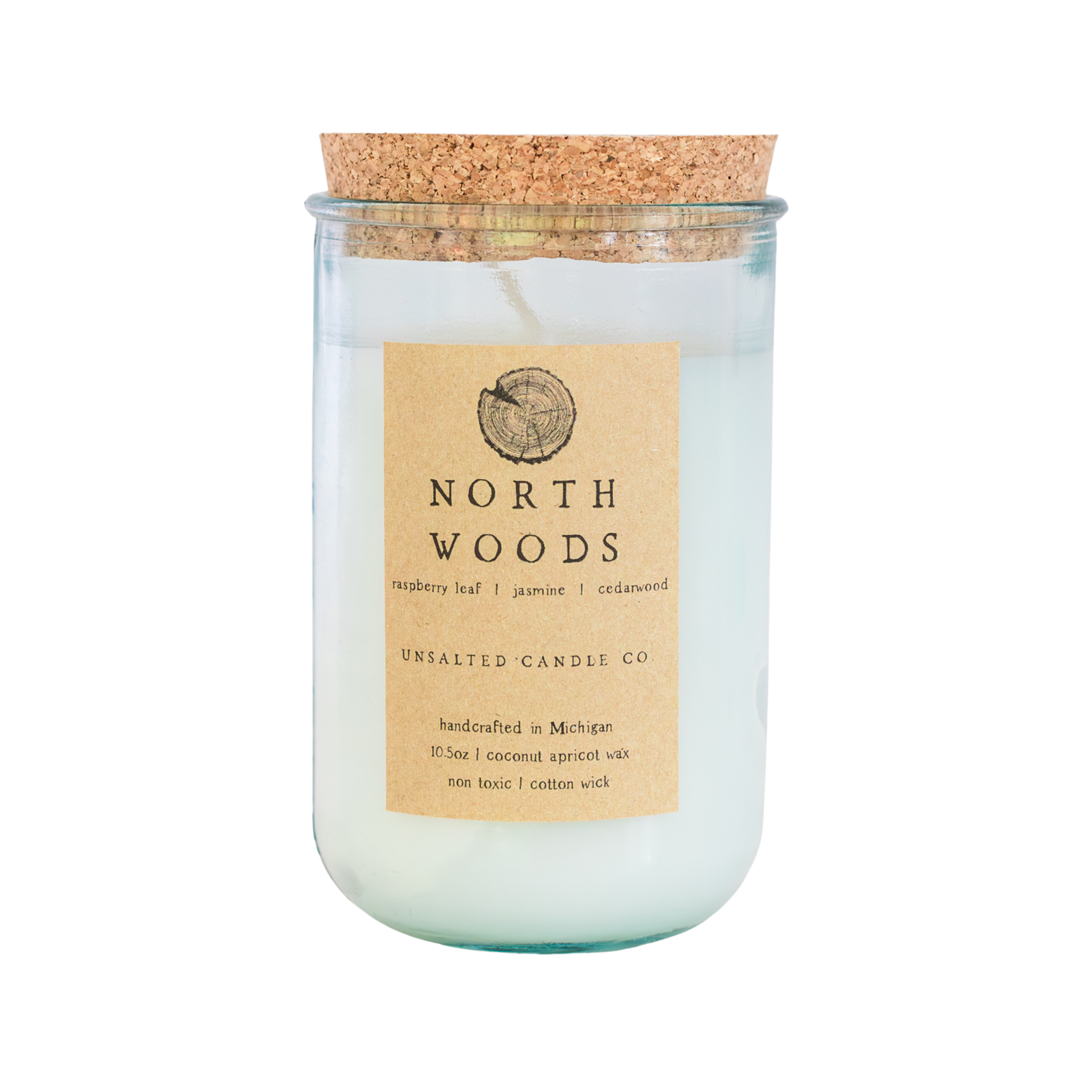 A North Woods scented candle by Unsalted Candle Co. in a clear glass jar with a cork stopper, featuring a light beige label with black text on a white background.