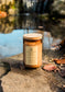 Candle labeled 'Michigan Man' on a rock with a blurred natural background